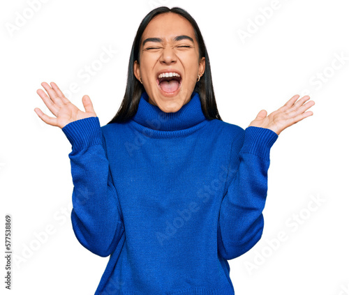 Young asian woman wearing casual winter sweater celebrating mad and crazy for success with arms raised and closed eyes screaming excited. winner concept