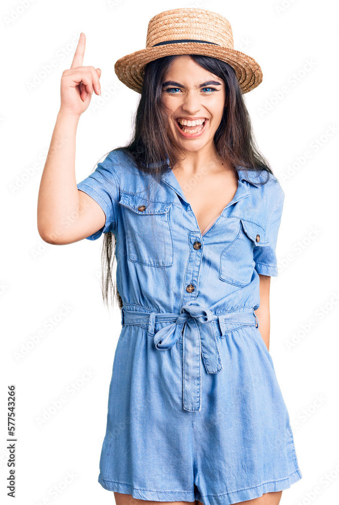 Brunette teenager girl wearing summer hat pointing finger up with successful idea. exited and happy. number one. Brunette teenager girl wearing summer hat pointing finger up with successful idea. exited and happy. number one.