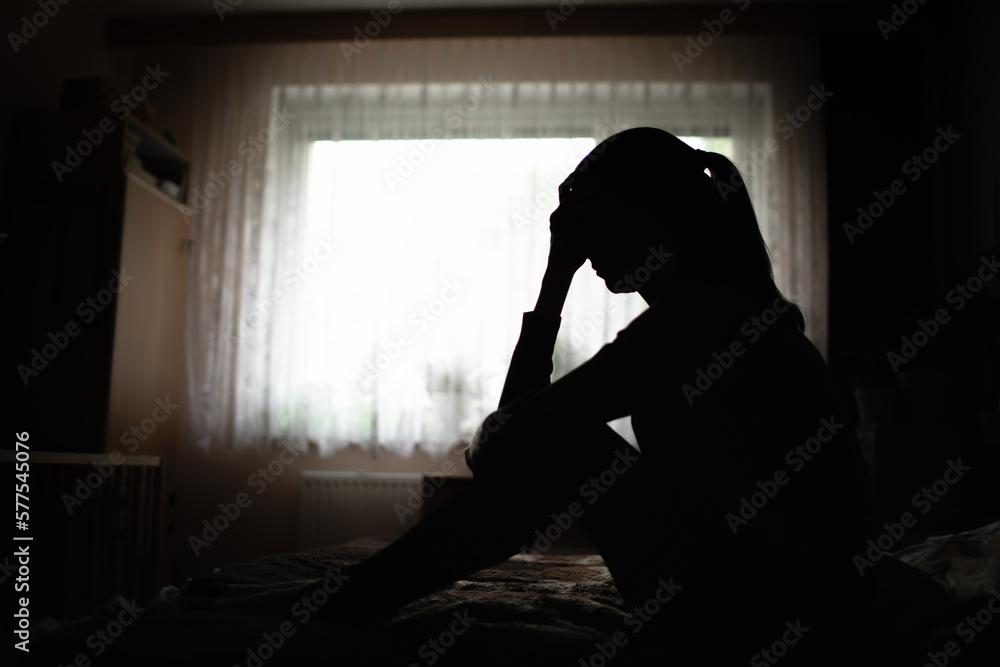silhouette of a woman sitting on bed feeling sleepless, suffering from emotional stress 