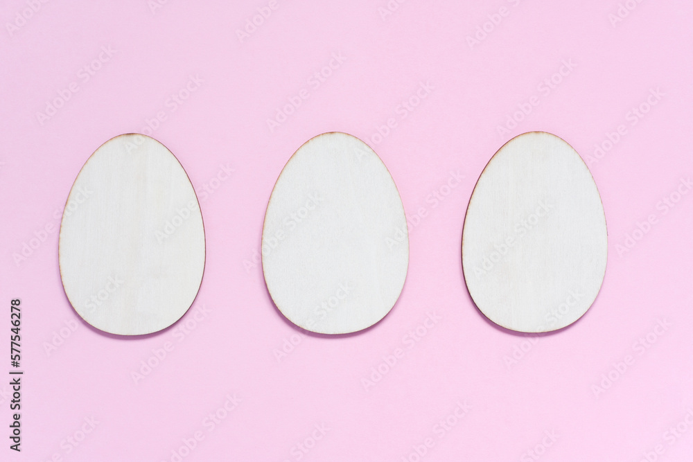 Three flat wooden blanks for creativity in shape of egg on pastel pink background. Happy Easter concept. Mockup for greeting card with space for text. top view, flat lay Three flat wooden blanks for creativity in shape of egg on pastel pink background. Happy Easter concept. Mockup for greeting card with space for text. top view, flat lay