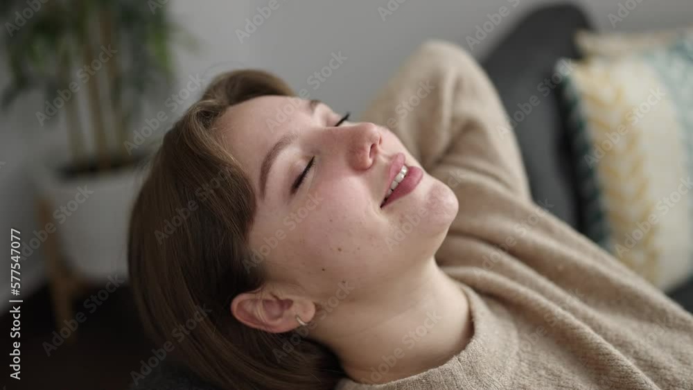 Young blonde woman relaxed with hands on head sitting on sofa at home Young blonde woman relaxed with hands on head sitting on sofa at home