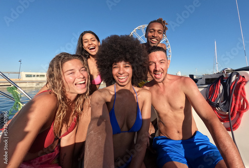 Happy young friends taking selfie with action camera while doing sea tour with sailing boat - concept of an organised trip for young people © Vittorio Gravino