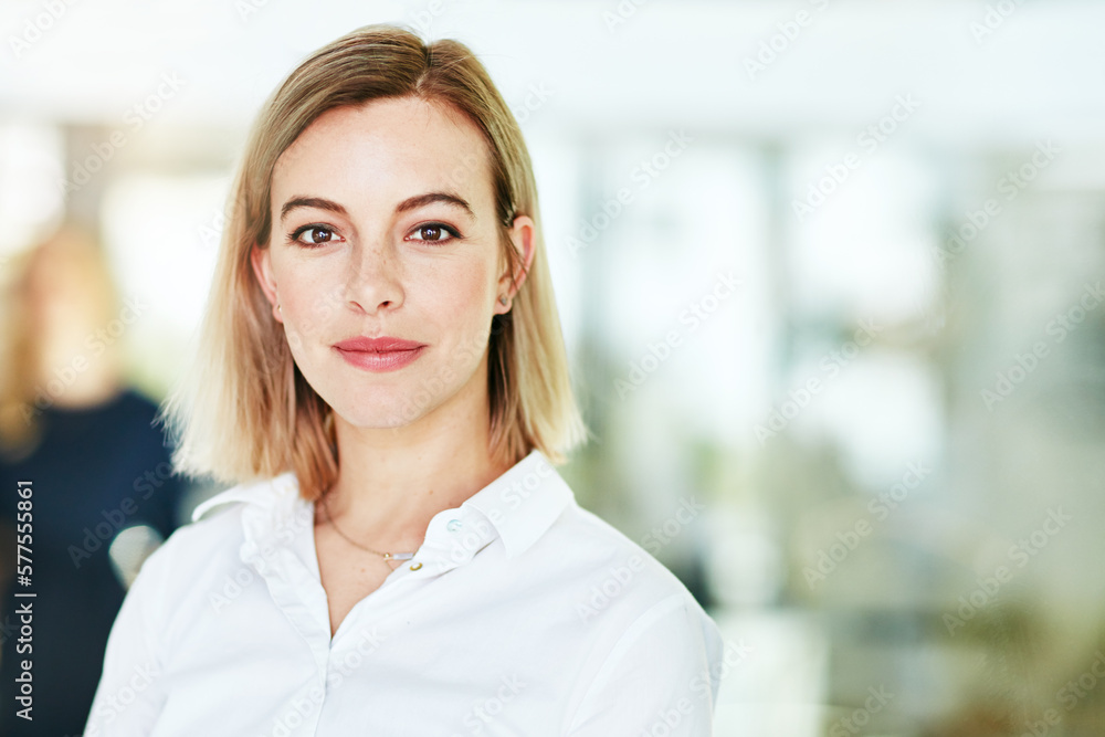 Here to do some serious business. Portrait of an ambitious young woman standing in a modern office with her colleagues in the background.