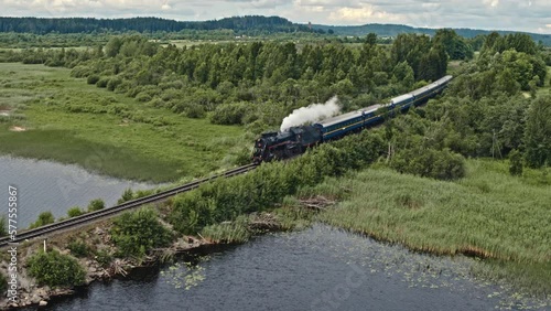 Steam locomotive pass over the water aerial view. Summer time.
