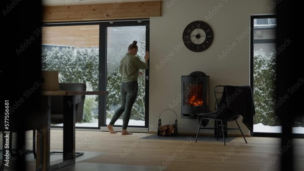 Female is closing the glass door to the garden. Female is closing the glass door to the garden.