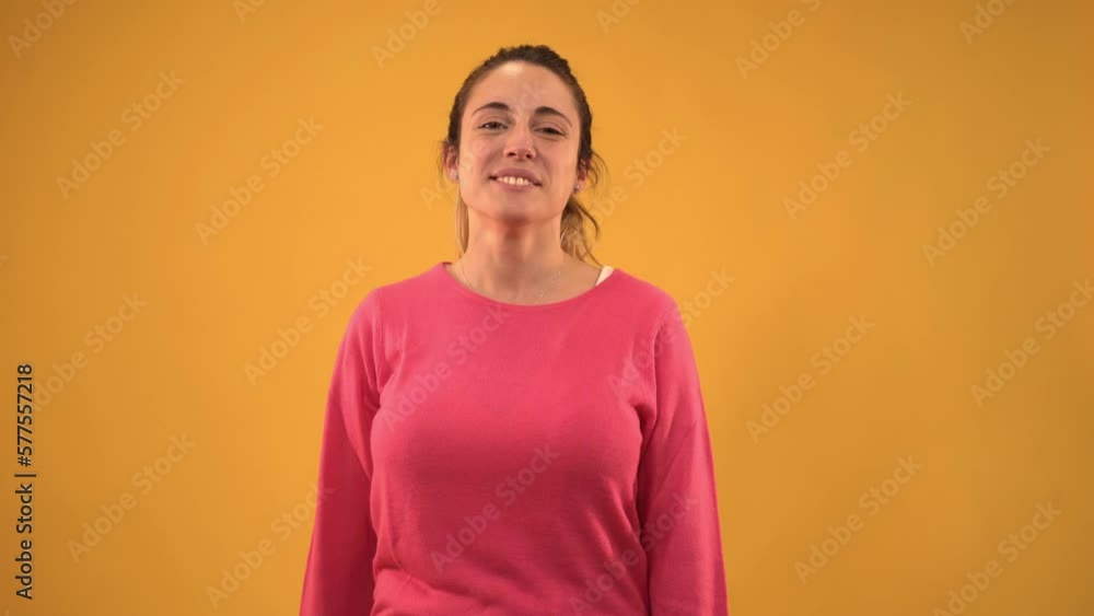 Young smiling girl looking camera and making thumbs up with hand. White woman with blonde hair on isolated background. Chroma yellow screen. Concept of giving the ok. Young smiling girl looking camera and making thumbs up with hand. White woman with blonde hair on isolated background. Chroma yellow screen. Concept of giving the ok.