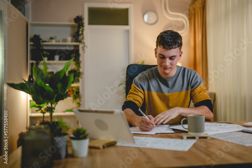 Young caucasian man teenager student study at home at the table night photo