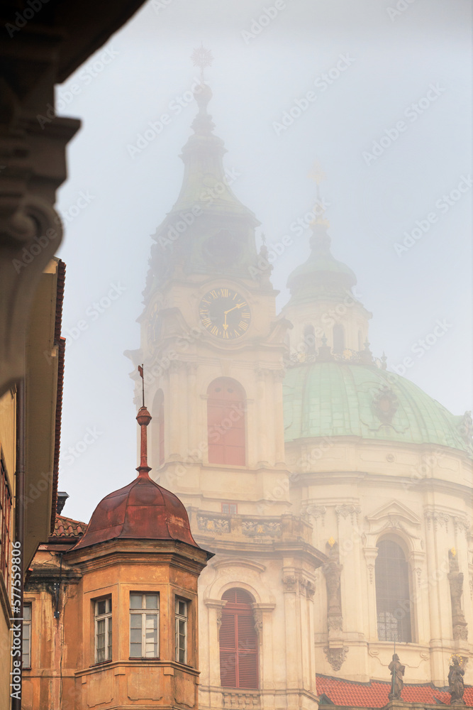 Cityscape on a foggy morning - view of the Church of Saint Nicholas in the Mala Strana historical neighbourhood of Prague, Czech Republic
