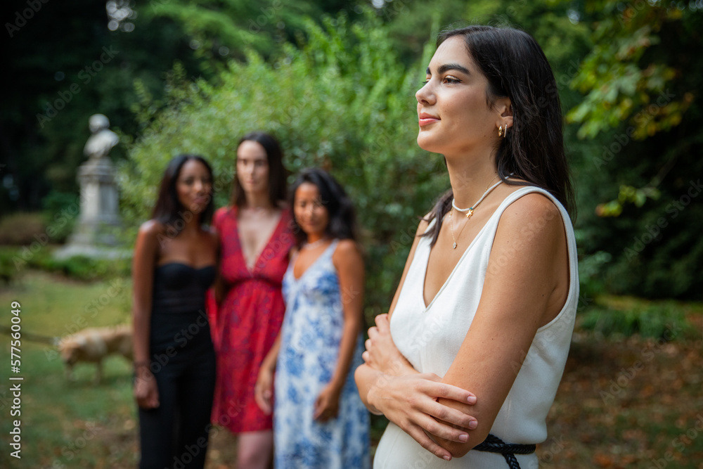 A young woman looks to the side with her friends behind out of focus, concept of women and unity A young woman looks to the side with her friends behind out of focus, concept of women and unity