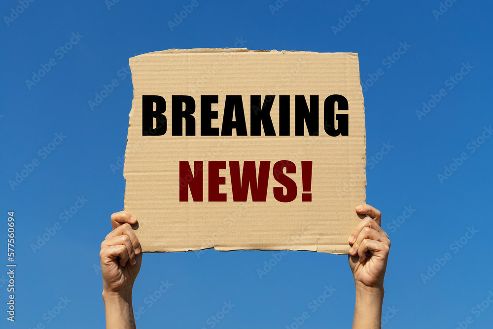 Breaking news message on box paper held by 2 hands with isolated blue sky background. This message board can be used as business concept to inform audience that there is breaking news. Breaking news message on box paper held by 2 hands with isolated blue sky background. This message board can be used as business concept to inform audience that there is breaking news.