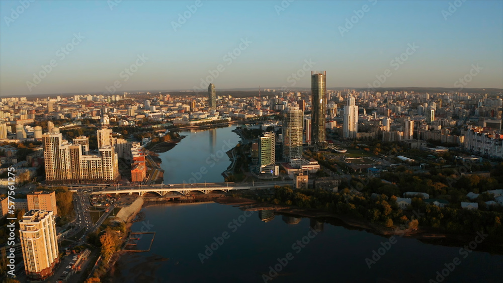 Top view of modern city with river with horizon at dawn. Stock footage. Beautiful city with high-rises and reflection in river at dawn. Panorama of modern city on background horizon in rays of dawn