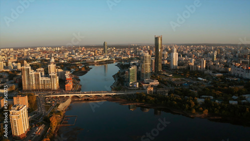 Top view of modern city with river with horizon at dawn. Stock footage. Beautiful city with high-rises and reflection in river at dawn. Panorama of modern city on background horizon in rays of dawn
