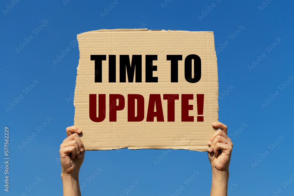 Time to update text on box paper held by 2 hands with isolated blue sky background. This message board can be used as business concept to inform audience that it is now time to update new information. Time to update text on box paper held by 2 hands with isolated blue sky background. This message board can be used as business concept to inform audience that it is now time to update new information.
