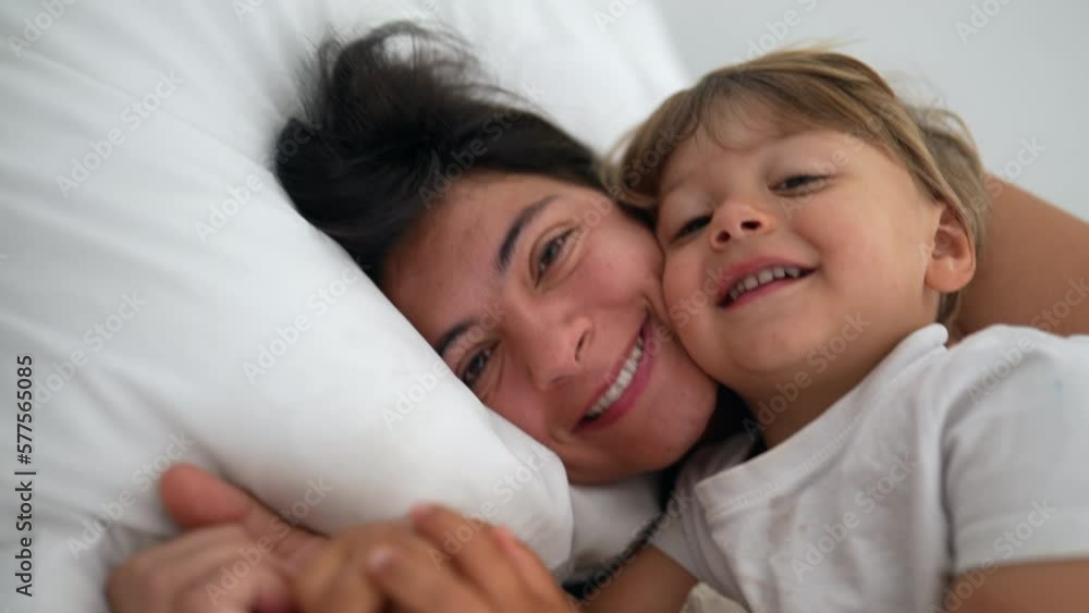 Mother and child son laying in bed together in authentic real life lifestyle moment. Motherhood love and affection with child in morning weekend Mother and child son laying in bed together in authentic real life lifestyle moment. Motherhood love and affection with child in morning weekend