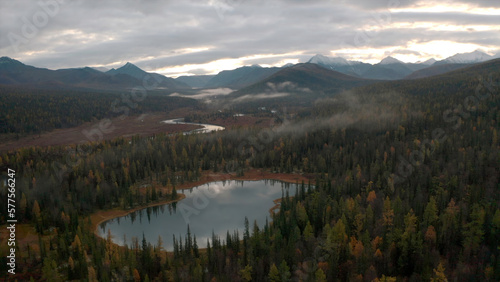 Top view of mountain landscape with forest and lakes in autumn. Clip. Landscape with forest mountains and lakes with river on cloudy autumn day. Cloudy wild landscape of mountain forest and lakes