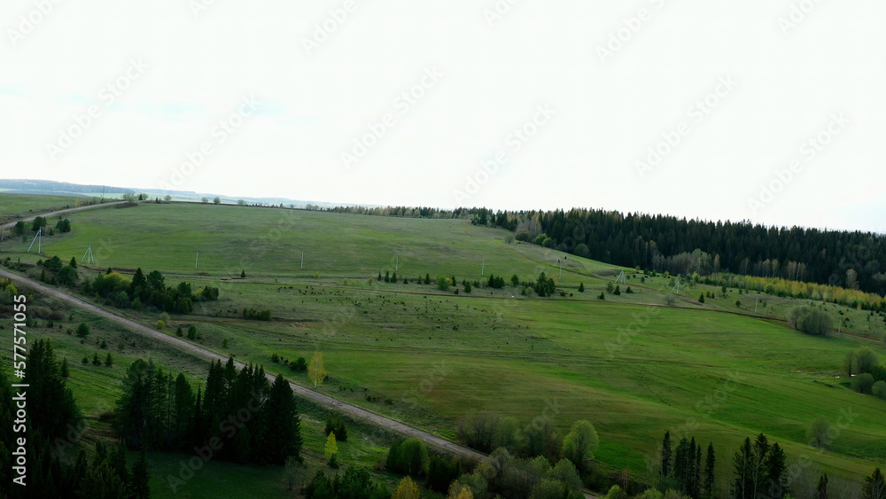 A quiet view of a provincial town next to a forest. Clip.Summer green landscape with small houses, gardens and farm and forest with fields around.