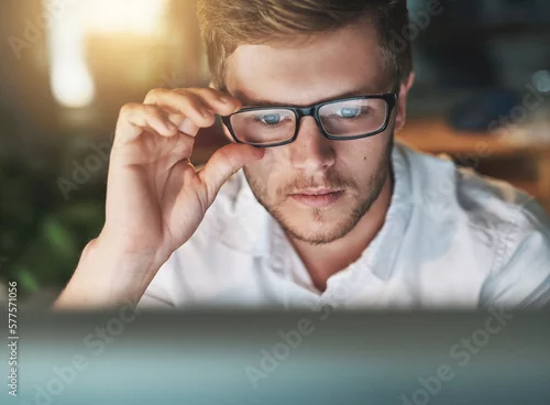 Obraz Am I seeing this right. Shot of a young designer adjusting his glasses as he looks at his computer screen.