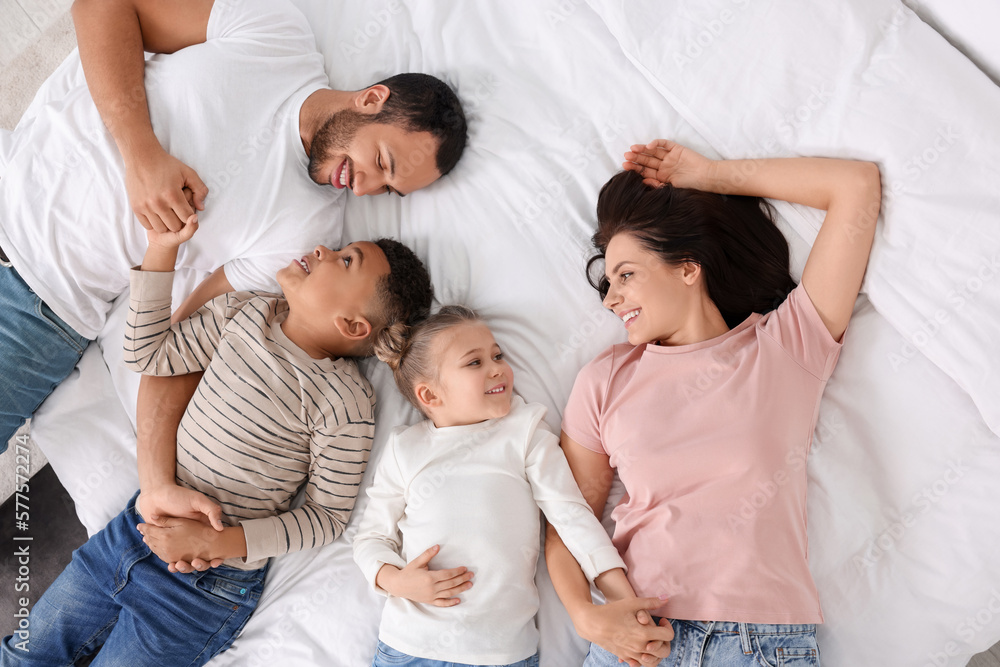 Happy international family lying on bed, top view