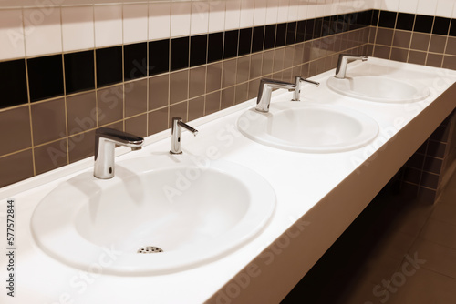 Row of clean ceramic sinks in public toilet