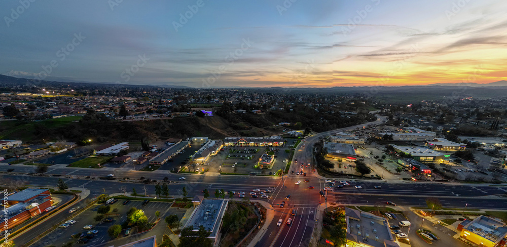 Fototapeta premium An Aerial View of the Sun Going Down over Yucaipa, California, with a Super market Shopping Complex and Traffic Below