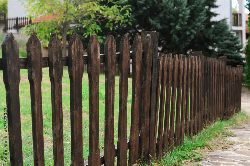 Low wooden fence near trees and green grass outdoors