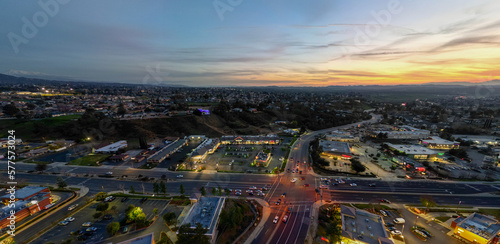 An Aerial View of the Sun Going Down over Yucaipa, California, with a Super market Shopping Complex and Traffic Below photo