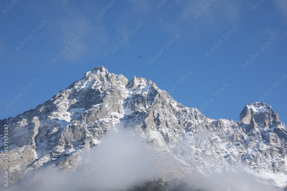 Picturesque landscape of high mountains covered with thick mist under blue sky