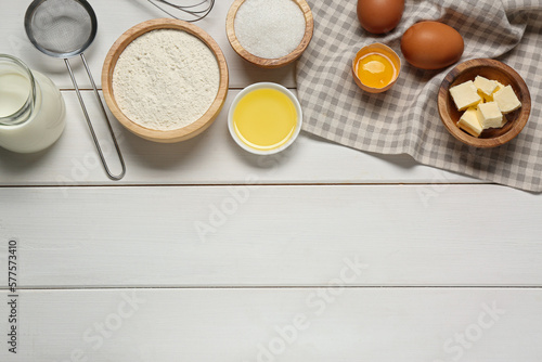 Ingredients for crepes on white wooden table  flat lay. Space for text