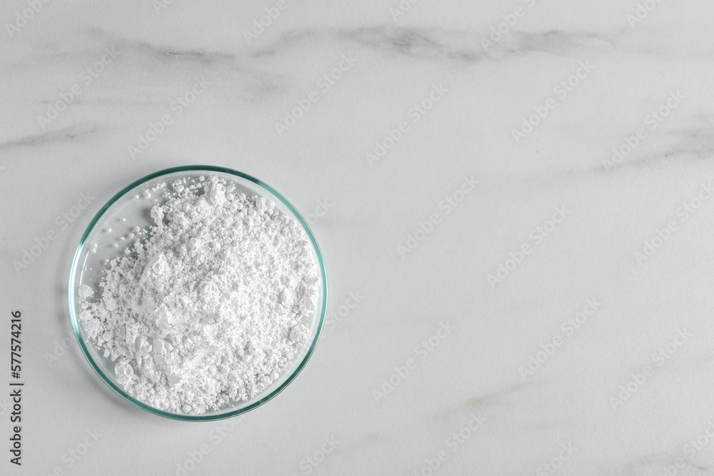 Petri dish with calcium carbonate powder on white marble table, top view. Space for text Stock