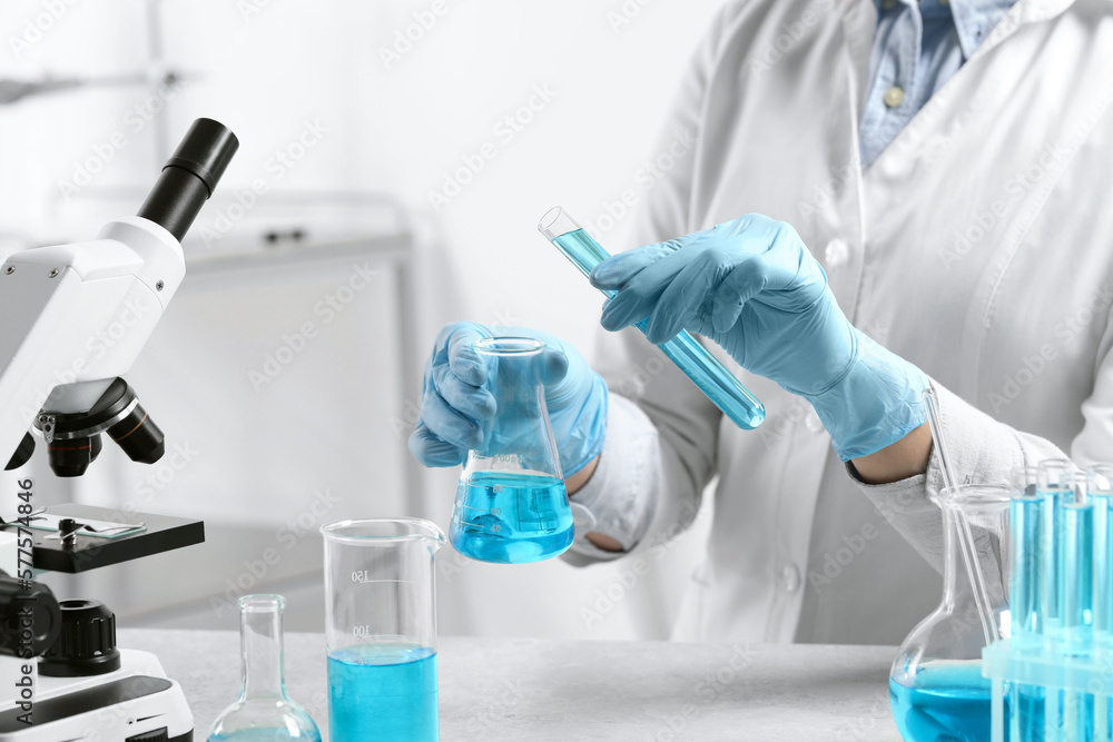 Scientist working with beaker and test tube in laboratory, closeup Scientist working with beaker and test tube in laboratory, closeup
