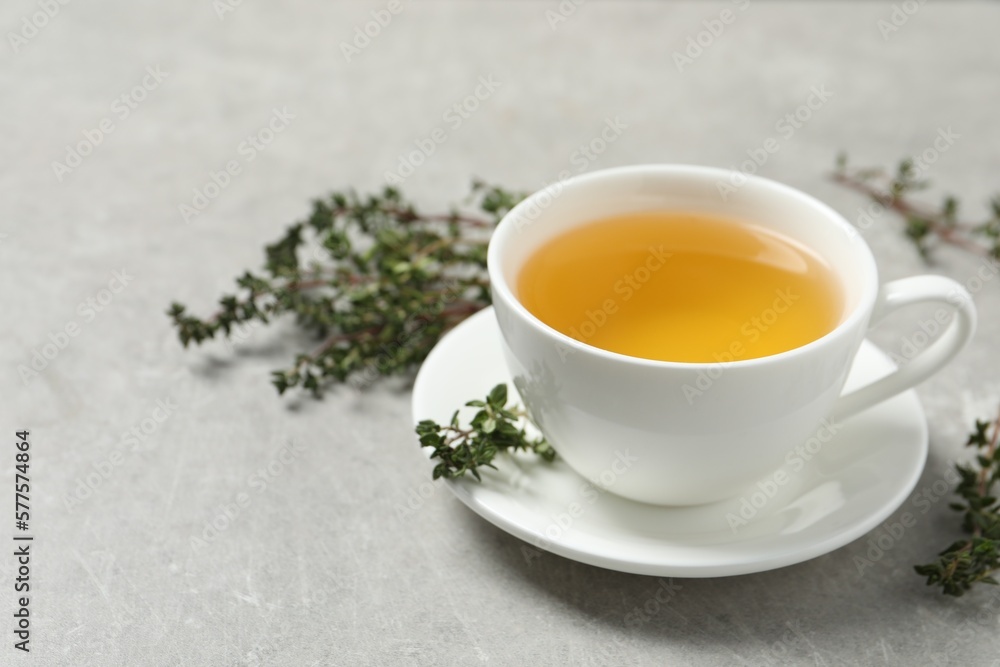 Aromatic herbal tea with thyme on light grey table. Space for text Aromatic herbal tea with thyme on light grey table. Space for text