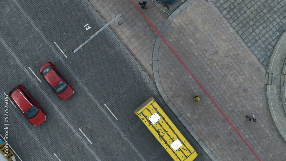 Fototapeta premium Top view of city road with traffic of cars. Stock footage. Urban highway with traffic of cars and people. Cars drive on city roads on cloudy day