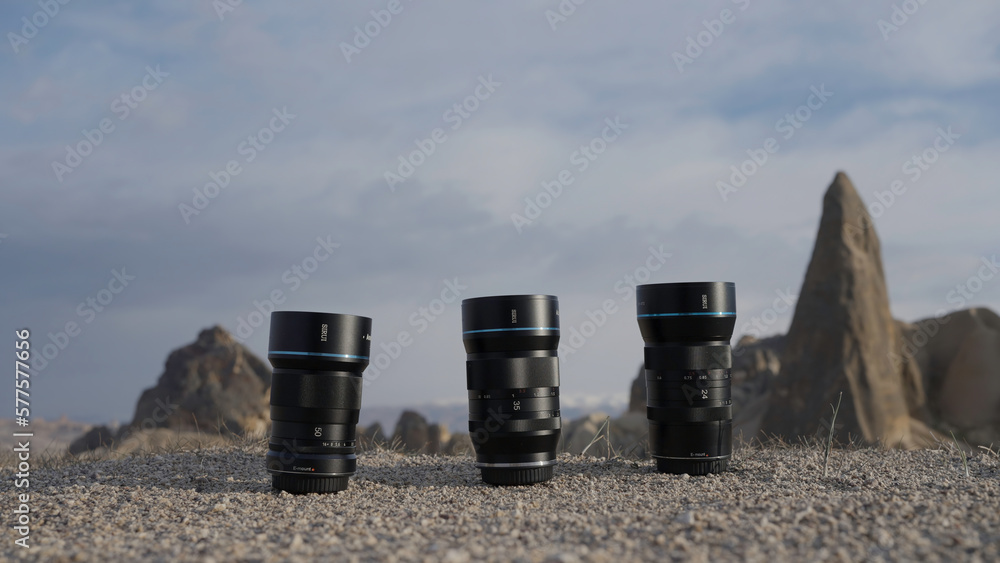 Three professional camera lenses. Action.Large black lenses from the camera that stand on the road of stones and you can see the gray sky.