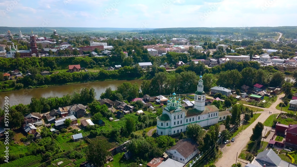 Top view of beautiful church in town by river in summer. Clip. Old colorful church in town by river on sunny day. Beautiful landscape of town with river and ancient churches in summer