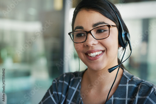 Shes a delight to speak to. Shot of a happy young woman using a headset at work.