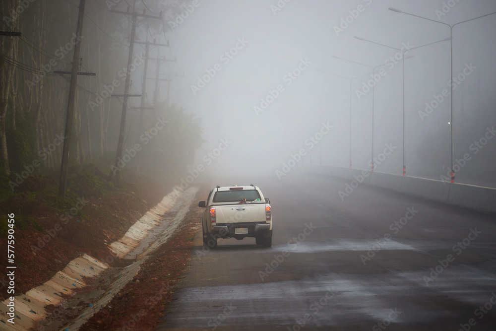 Car driving on the asphalt road with fog in early morning