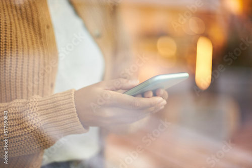 View through the window glass to the hands of unrecognizable woman using modern mobile phone indoors