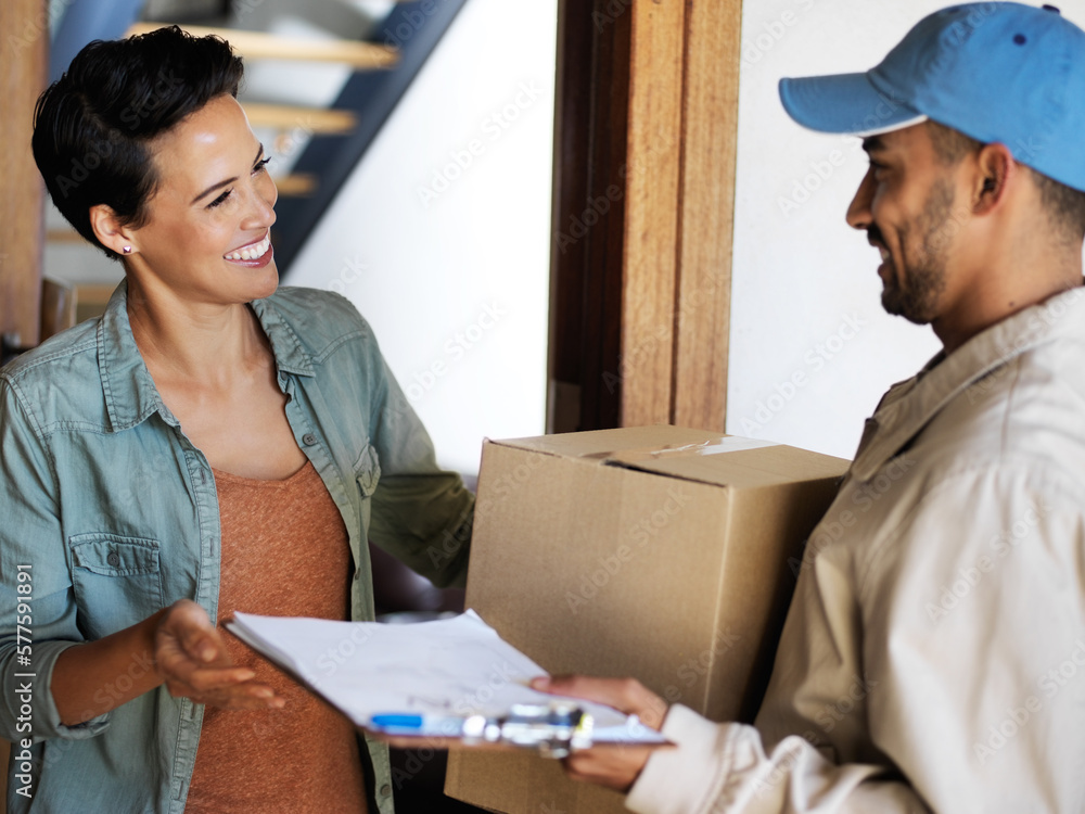 Keeping his clients smiling. Shot of a smiling young woman standing at her front door receiving a package from a courier. Keeping his clients smiling. Shot of a smiling young woman standing at her front door receiving a package from a courier.