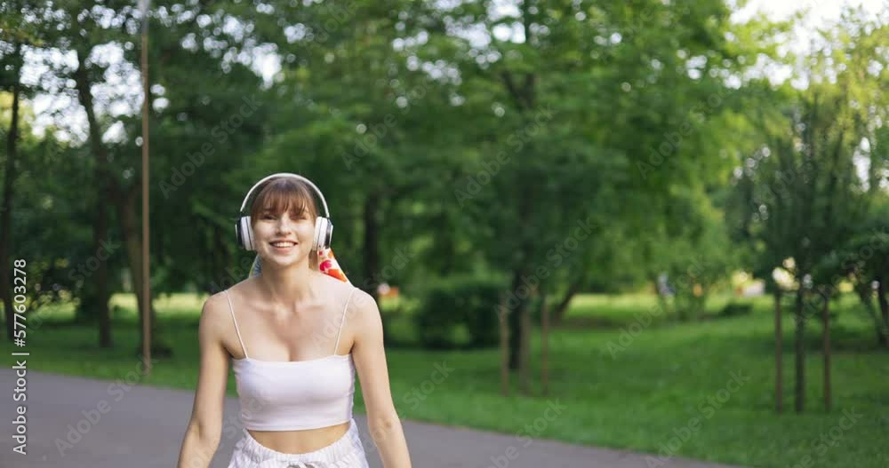 smiling skater girl in park doing pirouette and waving smiling skater girl in park doing pirouette and waving