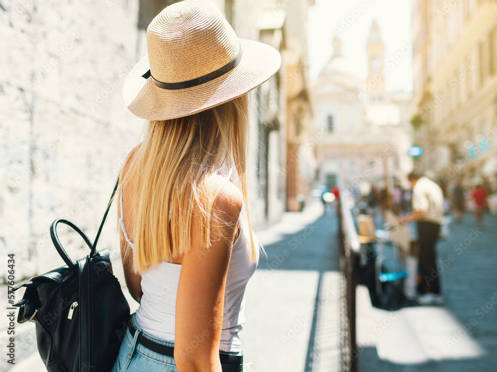 Young attractive smiling girl tourist exploring new city at summer