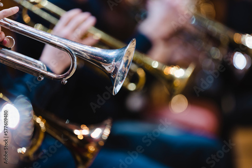 A musician playing a trumpet in a trumpet section of an orchestra during rehearsal