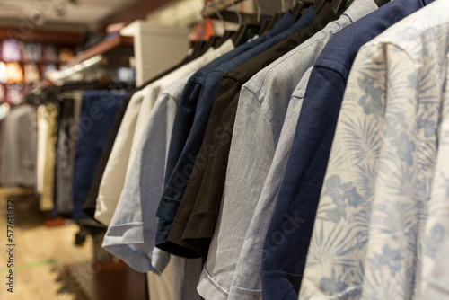 Men's casual shirts on hangers on a rail in a store. Summer collection of cotton and linen products. Side view. Close-up. Selective focus. © Анна Демидова