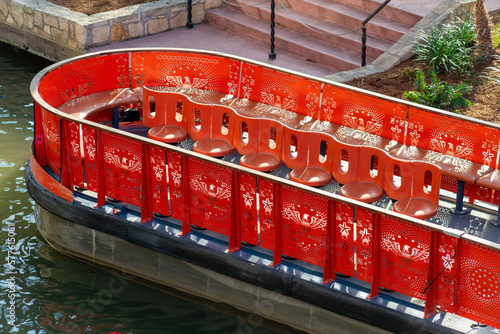 Red tour boat in the canals of san antonio texas in late afternoon shade in river with steps and cement embankment