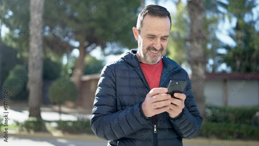 Middle age man smiling confident using smartphone at park Middle age man smiling confident using smartphone at park