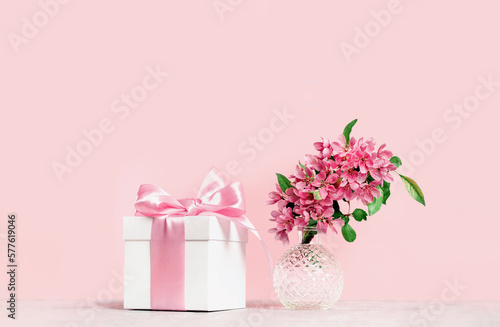 Pink pastel holiday. gift box and spring or summer flowers branch in a crystal ball vase. Monochrome., birthday or wedding. Valentines or Mothers day