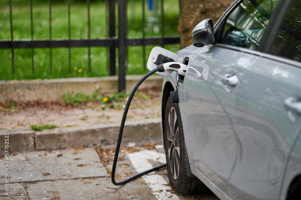 Charging an electric car with a plug connected to the car at a charging station.