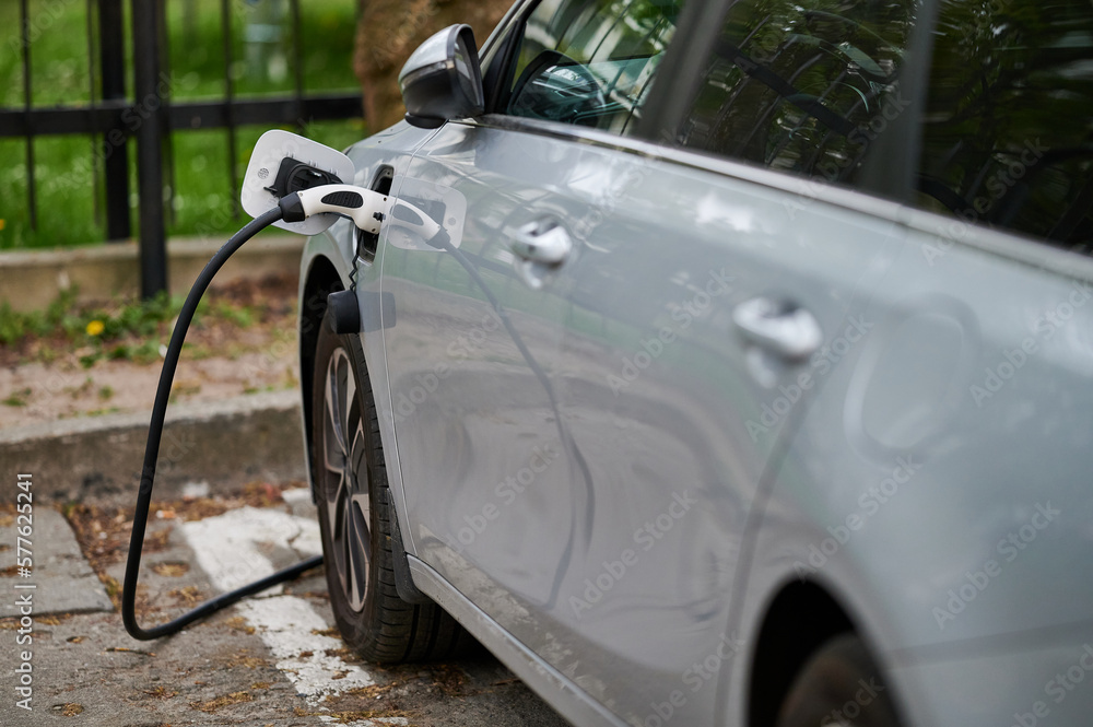 Charging an electric car with a plug connected to the car at a charging station.