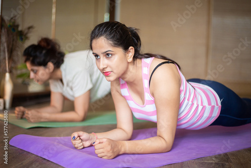 Young indian asian girls doing abdominal exercise workout at indoor yoga studio. Fat burn or weight loss. Selective focus 
