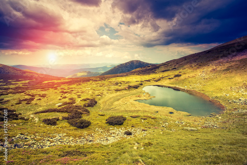 Picturesque mountains and a small lake illuminated by evening light. Carpathian mountains, Ukraine, Europe.