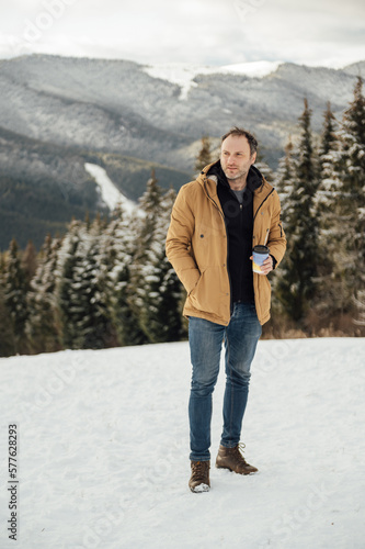 Morning coffee in the mountains. Handsome man drinking coffee and looking at the mountains in Ukraine.